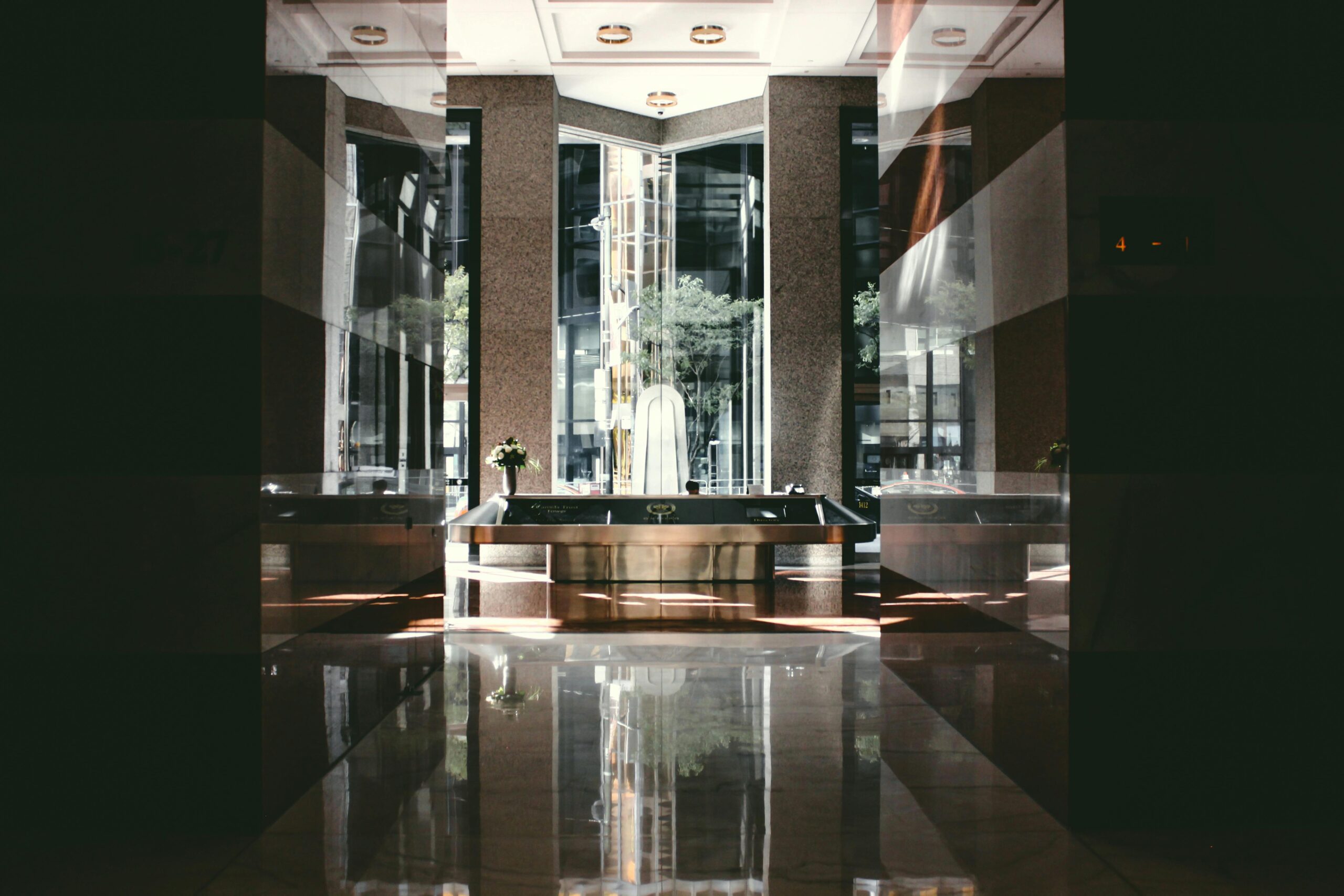 A sophisticated modern hotel lobby with glossy floors and natural light entering through large windows.